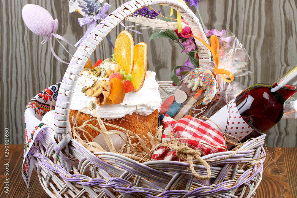 Decorative Easter basket with cake, colored eggs and liqueur. On a wooden table