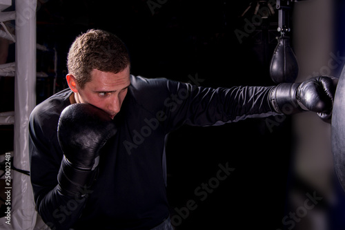 Boxer young man during a strike in training on a dark background