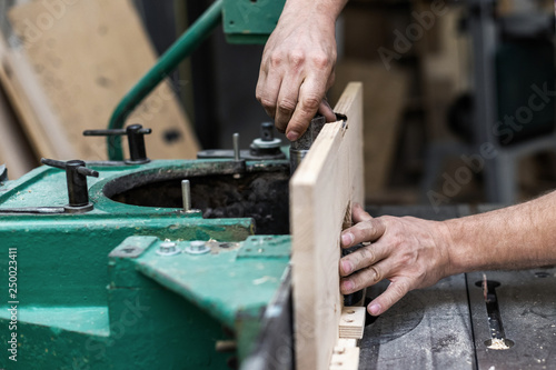 Hobby wood concept. Cropped photo of cabinetmaker handyman tradesman hands install wooden plank on woodworking machine make furniture in garage