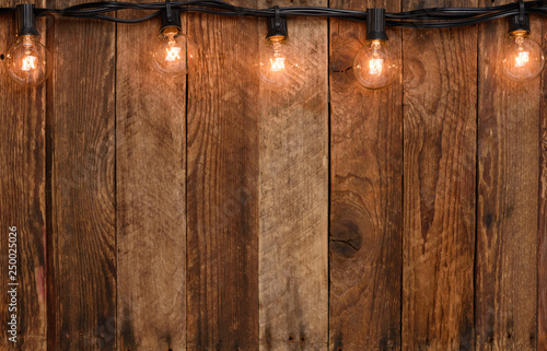 Obraz na plátně Vintage garland string lights on old wooden wall border with copy space
