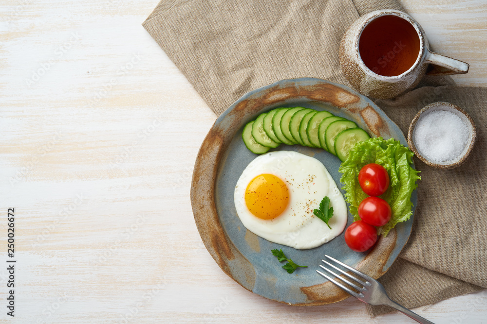 Fried egg, vegetables. Paleo, keto, fodmap diet. Copy space, top view. Healthy diet concept, blue plate on white wooden table