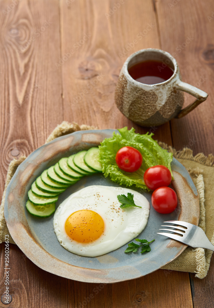Fried egg, vegetables. Paleo, keto, fodmap diet. Copy space, top view, vertical. Healthy diet concept, blue plate on old rustic wooden table Fried egg, vegetables. Paleo, keto, fodmap diet. Copy space, top view, vertical. Healthy diet concept, blue plate on old rustic wooden table