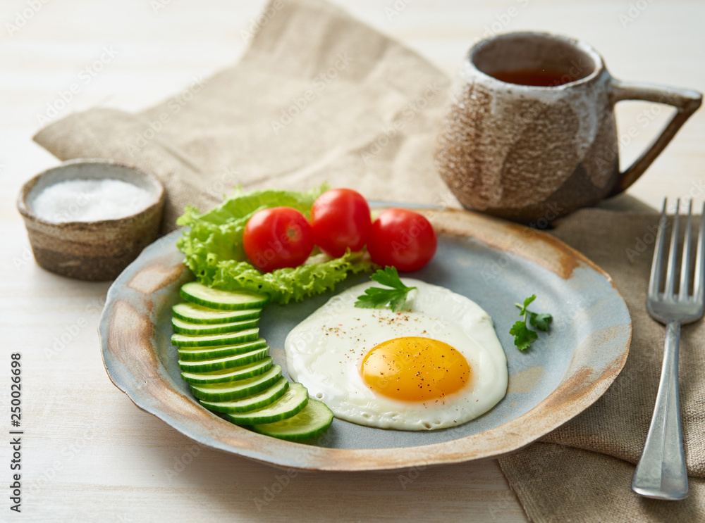 Fried egg, vegetables. Paleo, keto, fodmap diet. Copy space, side view. Healthy diet concept, blue plate on white wooden table Fried egg, vegetables. Paleo, keto, fodmap diet. Copy space, side view. Healthy diet concept, blue plate on white wooden table