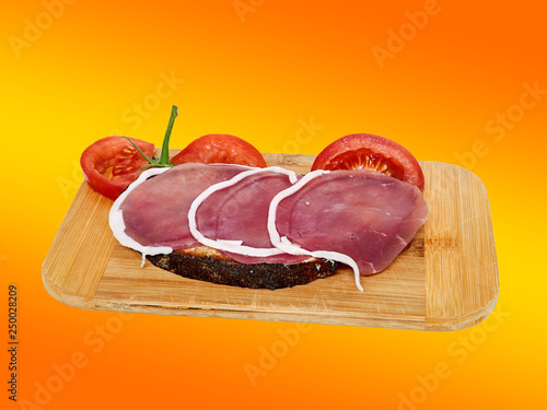 Ham bread on a wooden board, isolated against a orange background photo