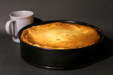 Fresh baked cheesecake in a brook shape, with a coffee cup, gray background