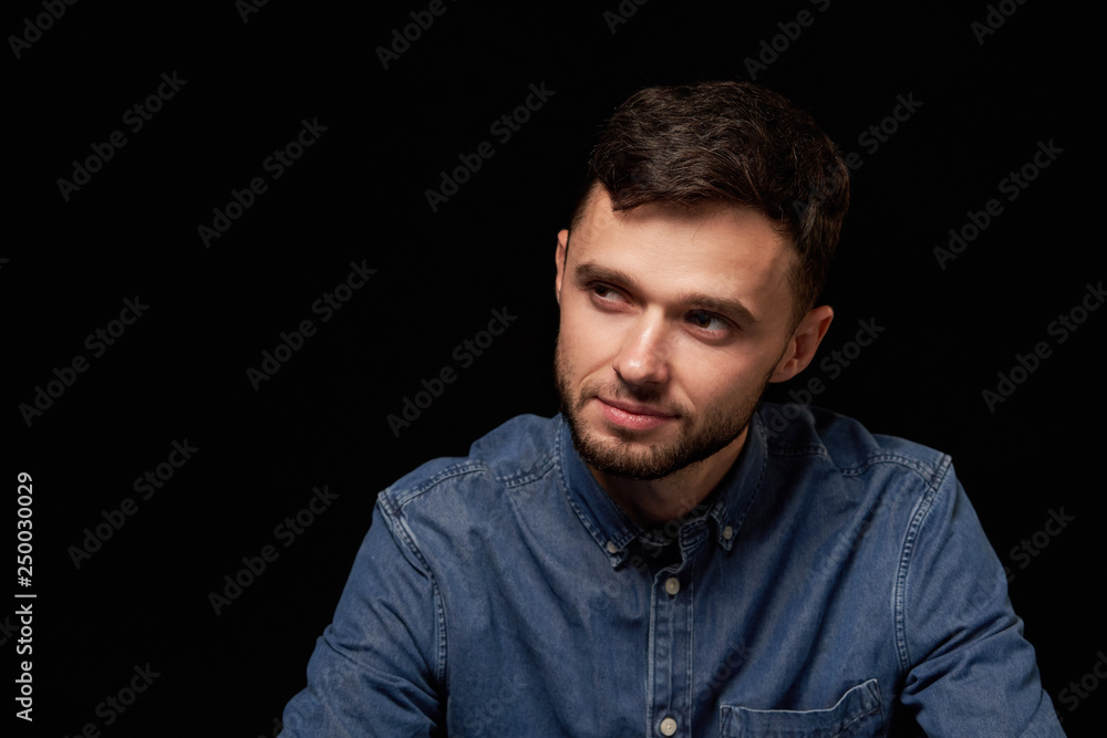 Fototapeta premium Man in denim shirt looking sideways with doubtful expression