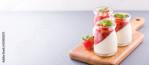 Delicous and nutritious double color (colour) strawberry desserts with mint and diced sarcocarp topping isolated with airy blue background, copy space, close up