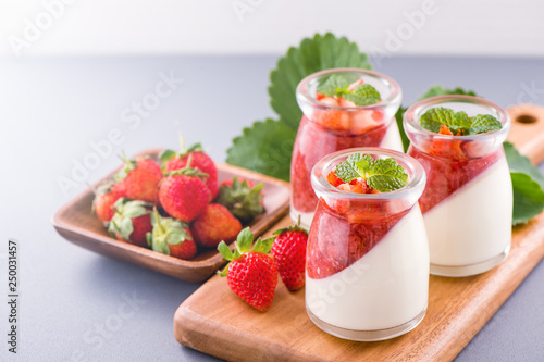 Delicous and nutritious double color (colour) strawberry desserts with mint and diced sarcocarp topping isolated with airy blue background, copy space, close up