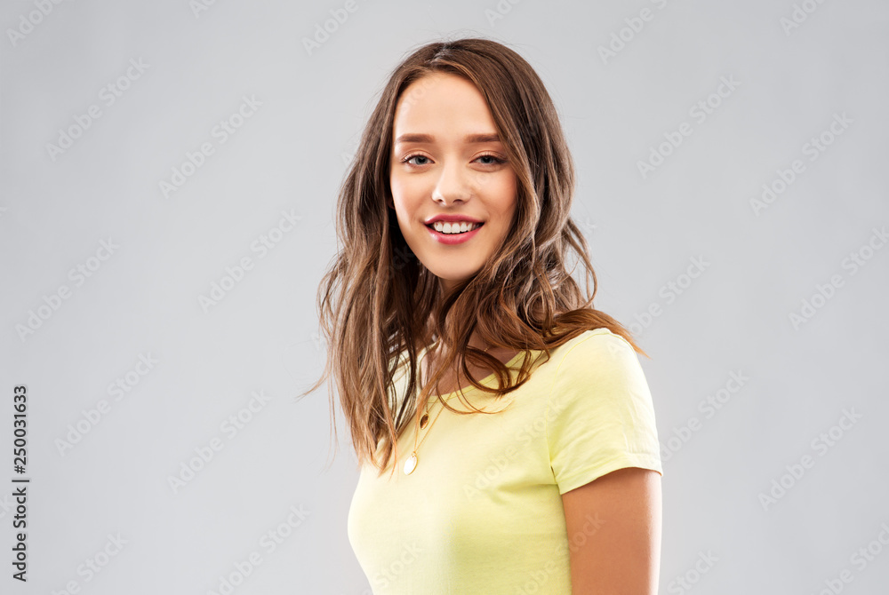people concept - smiling young woman or teenage girl in blank yellow t-shirt over grey background people concept - smiling young woman or teenage girl in blank yellow t-shirt over grey background