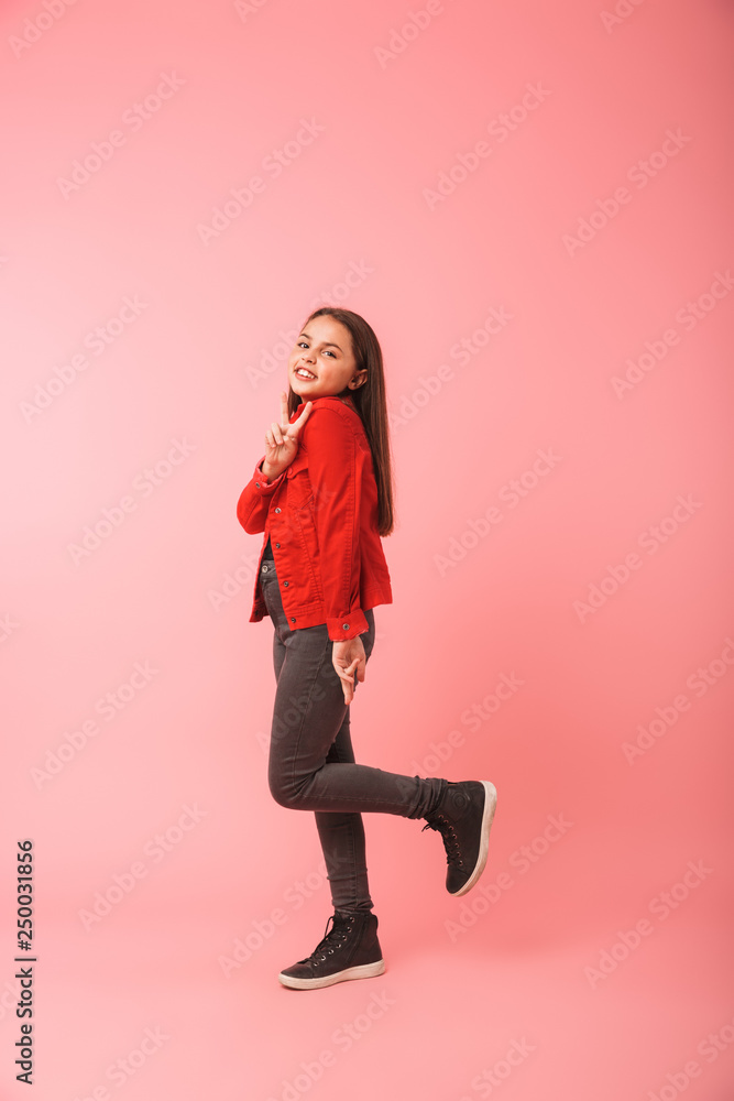 Full length photo of pretty girl in casual smiling while standing, isolated over red background