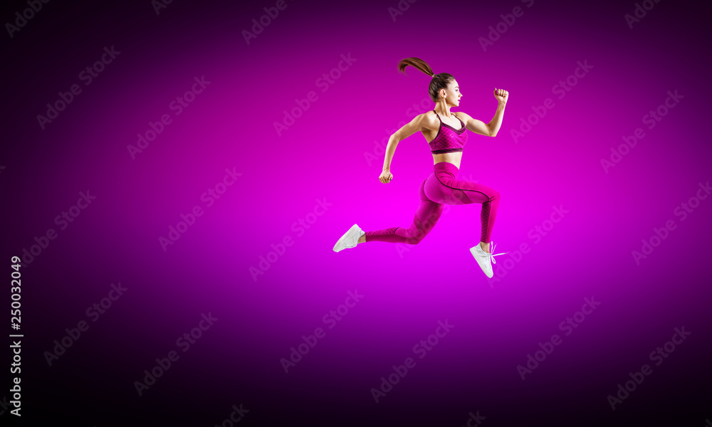 Young woman runner in purple sportswear jump in the air.