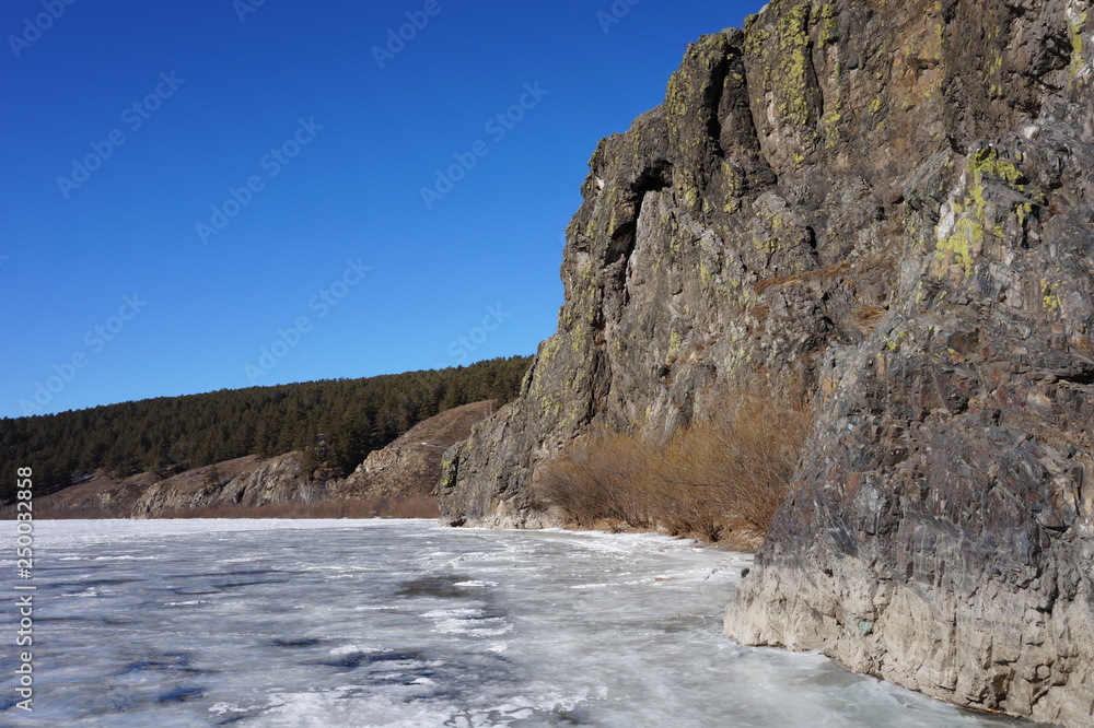 Mountain cliffs on the bank of the river against the blue sky Mountain cliffs on the bank of the river against the blue sky