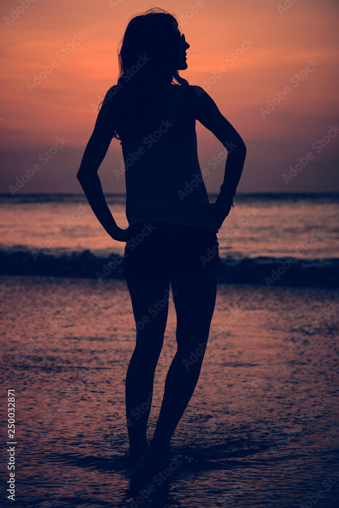 Fototapeta premium Silhouette of a girl in sunset / sunrise time over the ocean.