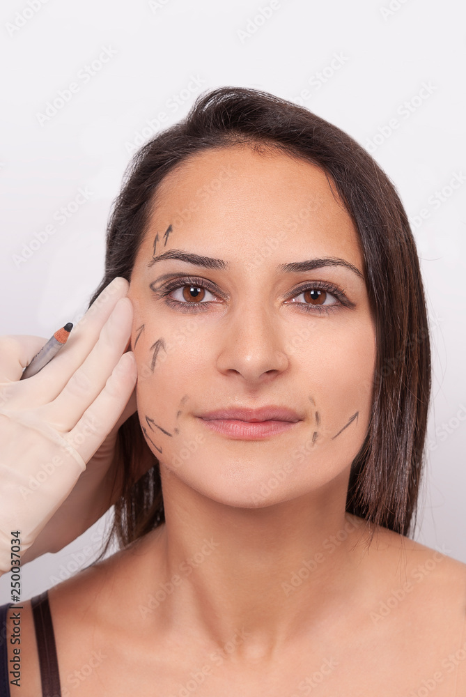 Surgeon drawing surgical lines on beautiful woman's face Surgeon drawing surgical lines on beautiful woman's face