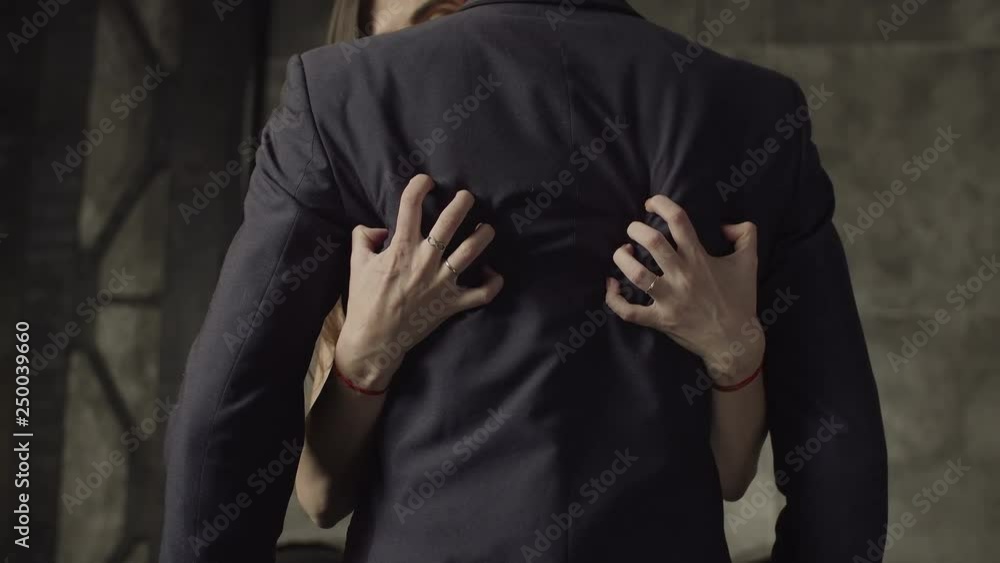 Close-up of woman's hands plugging manicured nails into man's back dressed in formal wear in night club. Midsection of passionate female flirting with confident businessman indoors. Close-up of woman's hands plugging manicured nails into man's back dressed in formal wear in night club. Midsection of passionate female flirting with confident businessman indoors.