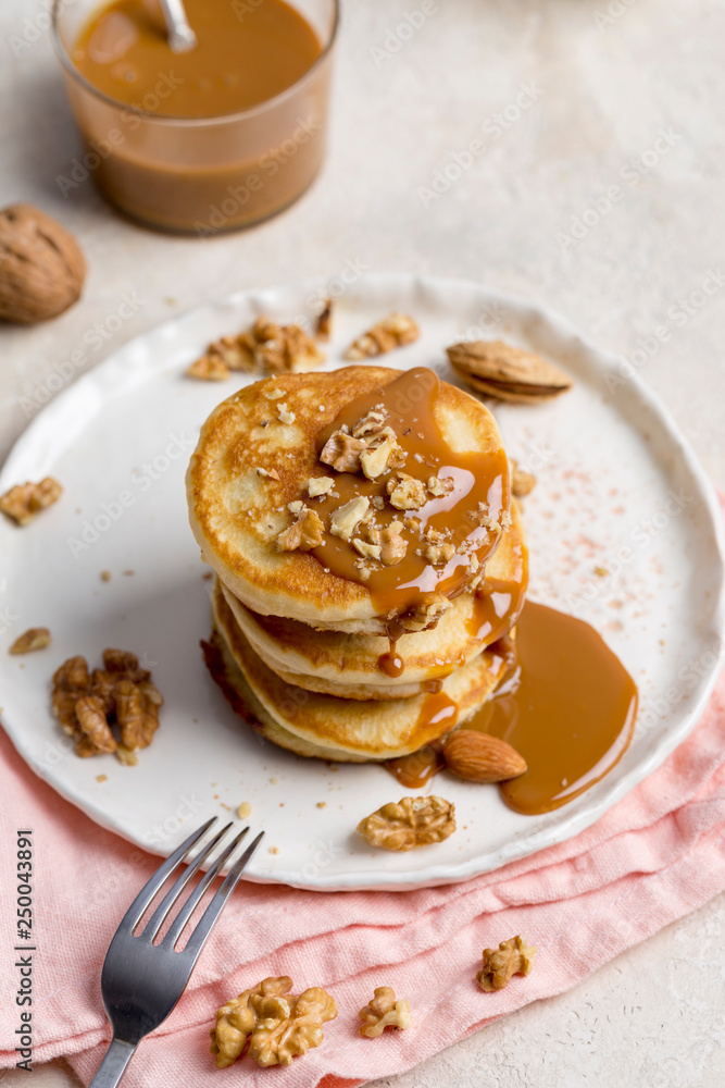 Stack of pancakes with caramel and walnuts on white plate Stack of pancakes with caramel and walnuts on white plate