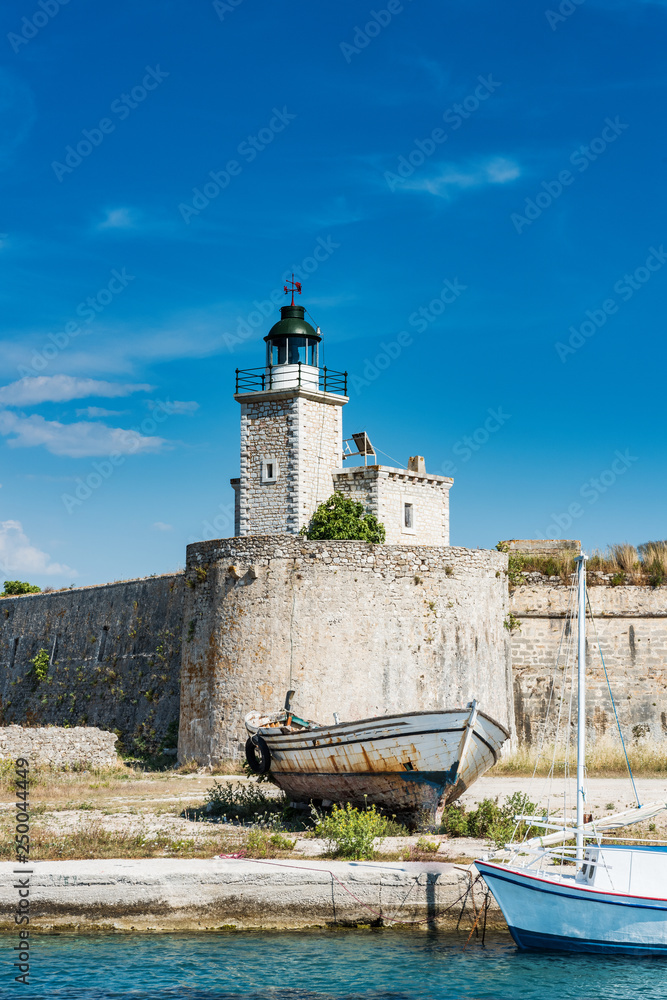 The old lighthouse on fortress wall. Below are two wooden ships.