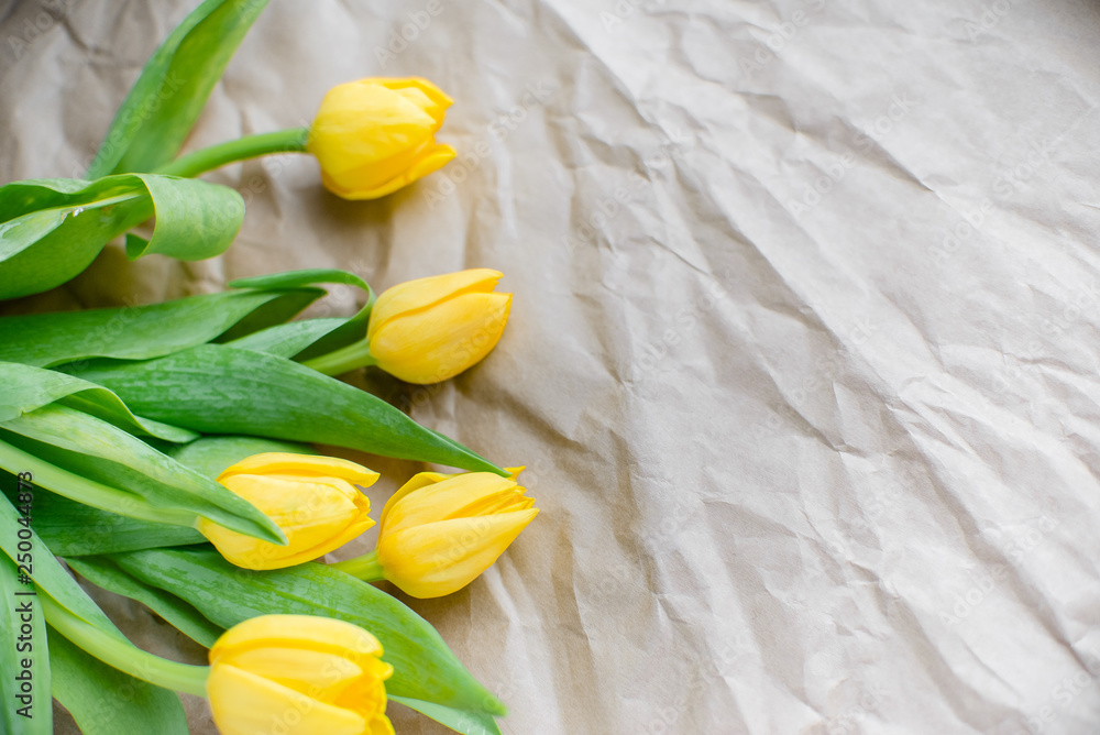 Obraz premium Bouquet of yellow tulips on wrapping paper. Valentine's Day and Mother's Day background. Top view Copy Space.