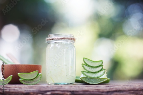 Fresh aloe vera plant, slices and gel on wooden background, skin therapy concept