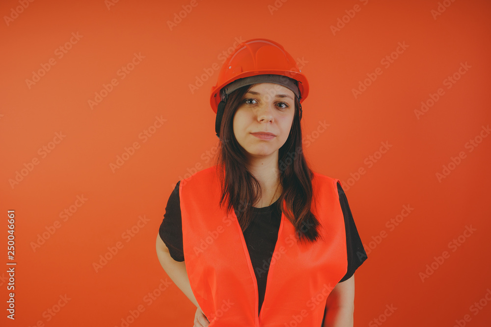 Girl construction worker, road worker or longshoreman, a woman in a helmet and orange vest Girl construction worker, road worker or longshoreman, a woman in a helmet and orange vest