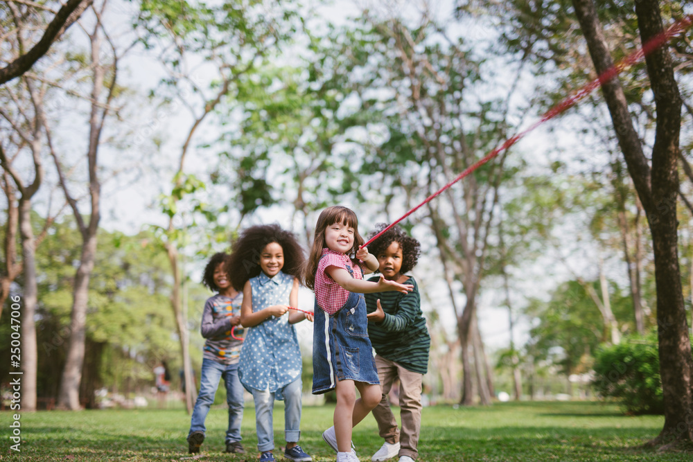 Group of children playing tug of war at the park.