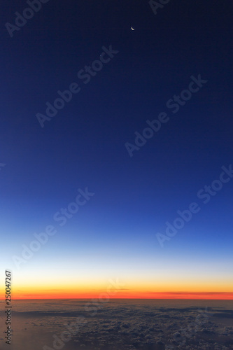 Beautiful aerial sunrise cloudscape with a new moon in the blue morning sky in the Netherlands © dennisvdwater
