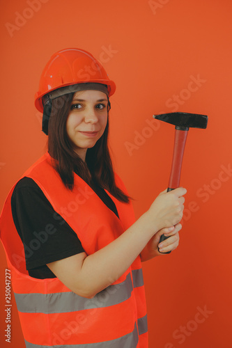 Girl construction worker, road worker or longshoreman, a woman in a helmet and orange vest