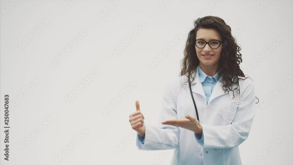 Smiling female doctor with a folder in a single standing. Smiling woman - a doctor. During this she is on a gray background. Smiling female doctor with a folder in a single standing. Smiling woman - a doctor. During this she is on a gray background.