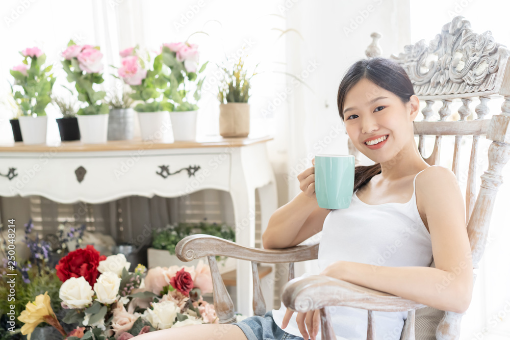 Portrait Asian woman relaxing on wooden chair with coffee at home