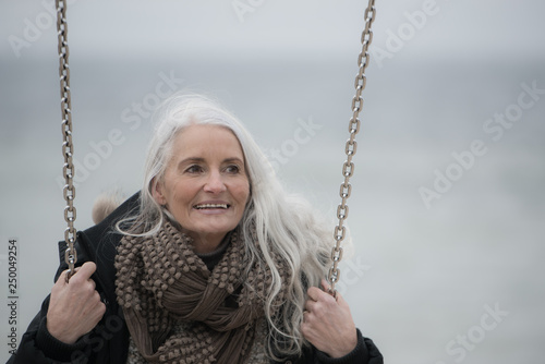 mature lady with long grey hair on a swing 