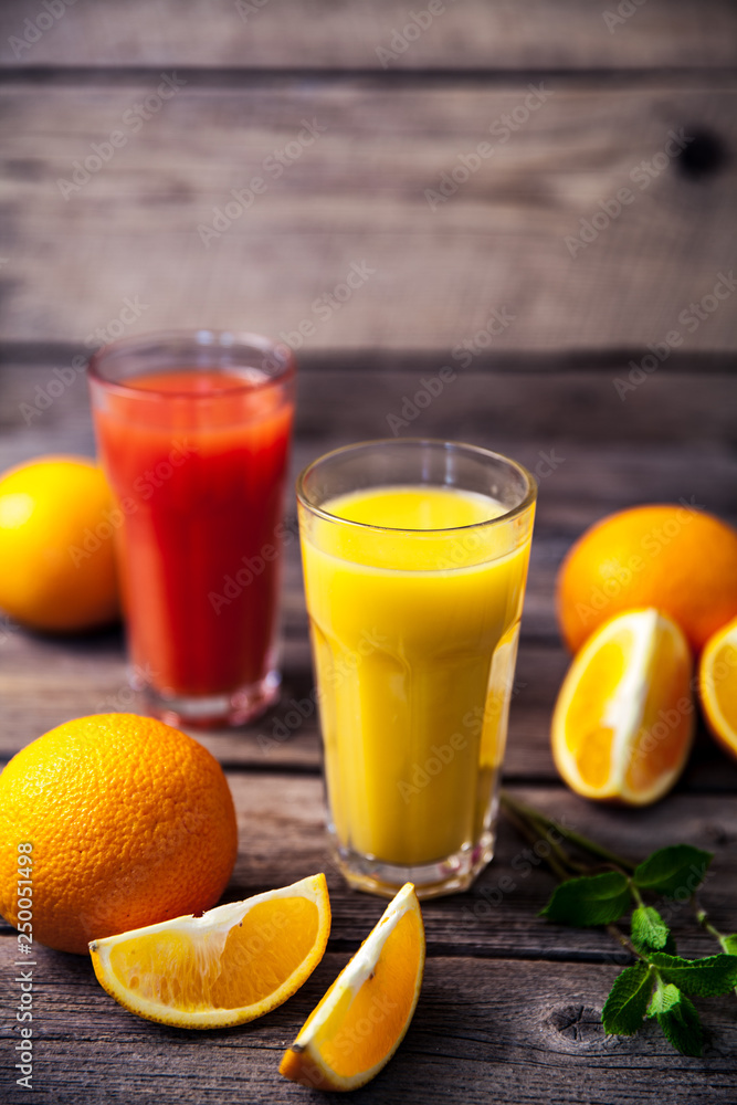 Orange juice in glass with mint, fresh fruits on wooden background Orange juice in glass with mint, fresh fruits on wooden background