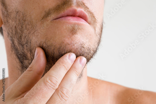 Man touching his short beard. Isolated on gray background. Men's issues. Face closeup. Front view. 
