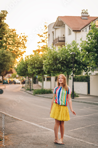 Summer portrait of pretty kid kid girl posing outdoors, wearing yellow skirt and colorful blouse © annanahabed