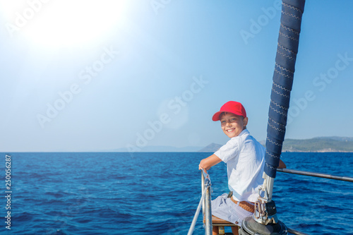 Little boy on board of sailing yacht on summer cruise. Travel adventure, yachting with child on family vacation. photo