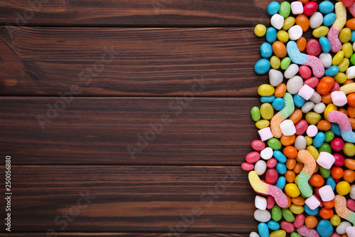 Colorful lollipops and different colored round candy on brown wooden background