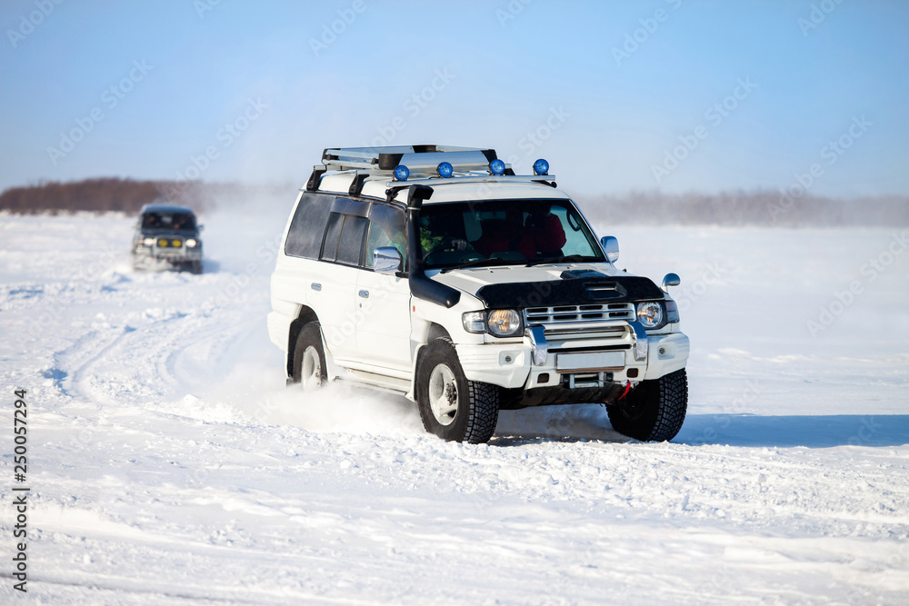 Two SUVs moving at snow field