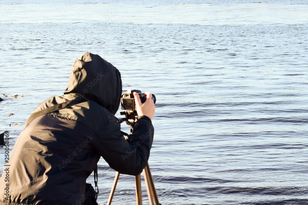 Obraz premium A girl with a camera photographs the sea. Naturalist photographer. Travel to Norway. North Sea.