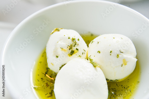 Goat cheese in olive oil and spices. Top view, white background, close up.