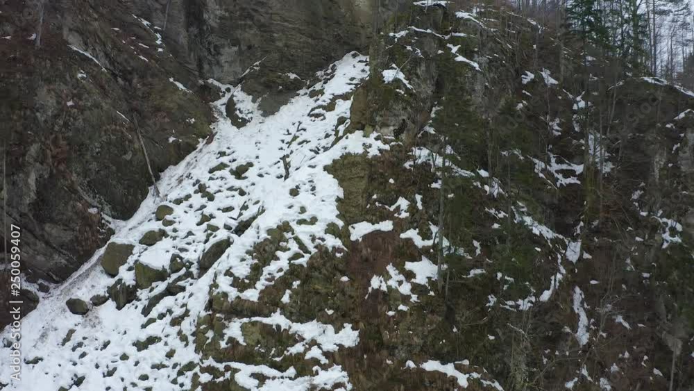 Drone rising along the face of a mountain with forests in the winter Drone rising along the face of a mountain with forests in the winter