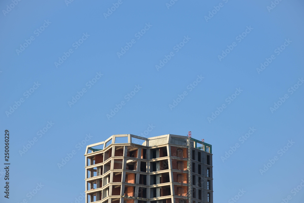 construction of gray skyscraper against blue sky and contrasts it construction of gray skyscraper against blue sky and contrasts it