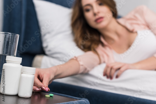 Cropped view of woman in bed taking medicine