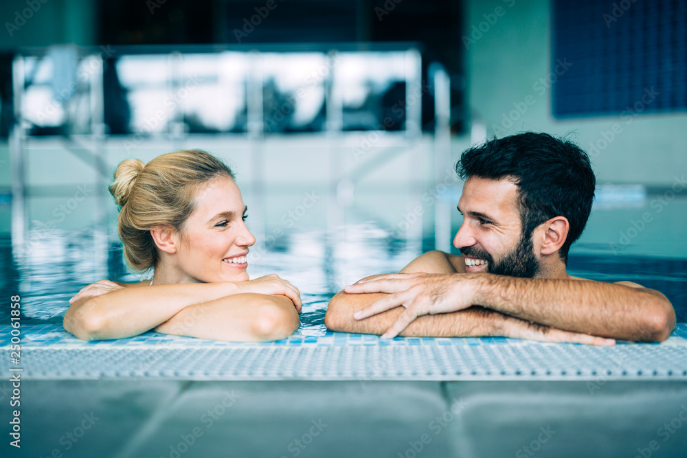 Happy attractive couple relaxing in swimming pool - obrazy, fototapety, plakaty 