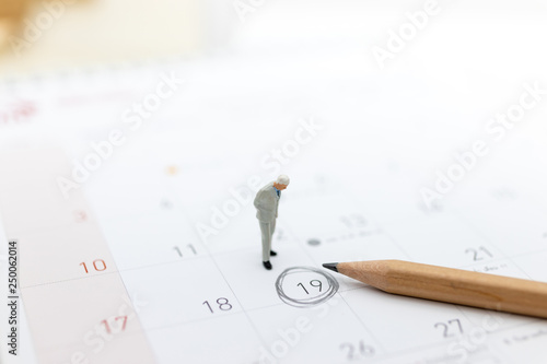 Miniature people : Businessman standing on the calendar to set the date for the meeting . Image use for business meetings concept.