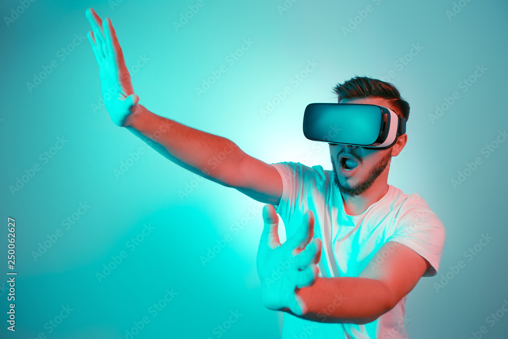 Handsome bearded man trying VR headset and exploring another world on the colorful background. Smartphone using with VR headset. Handsome bearded man trying VR headset and exploring another world on the colorful background. Smartphone using with VR headset.