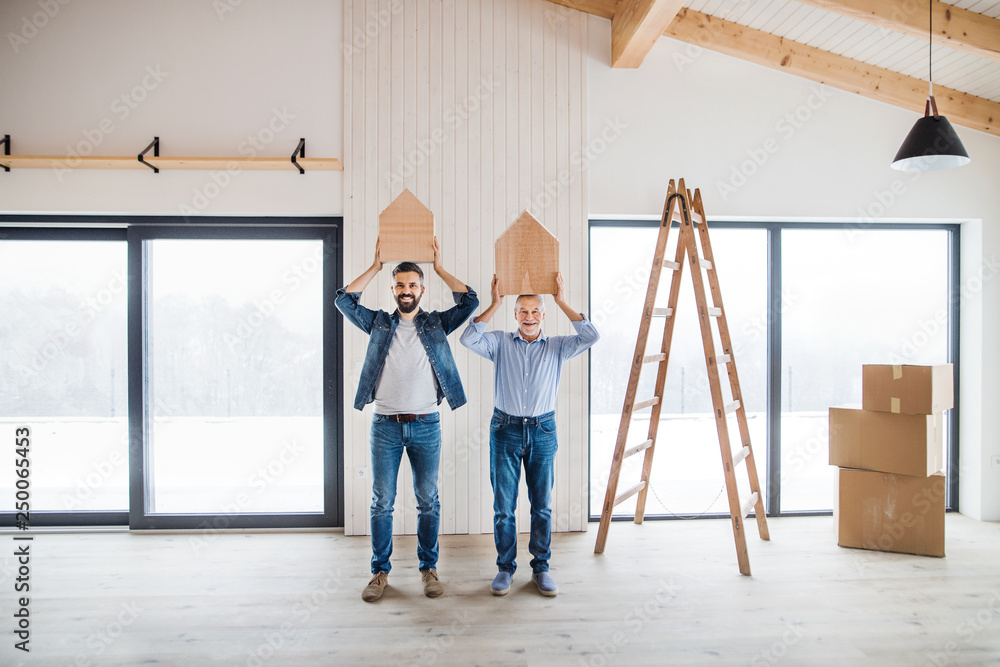 Two men holding small wooden houses on their heads when furnishing new house.