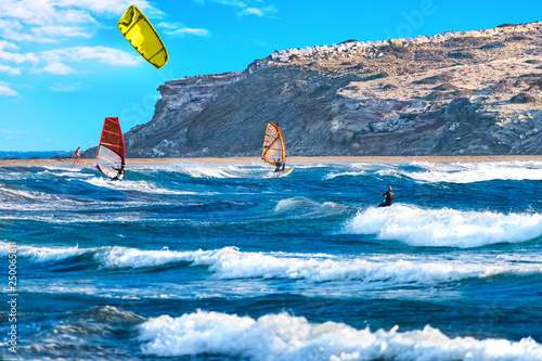 Two windsurfers and kiteboarder ride on Prasonisi beach (Rhodes, Greece)