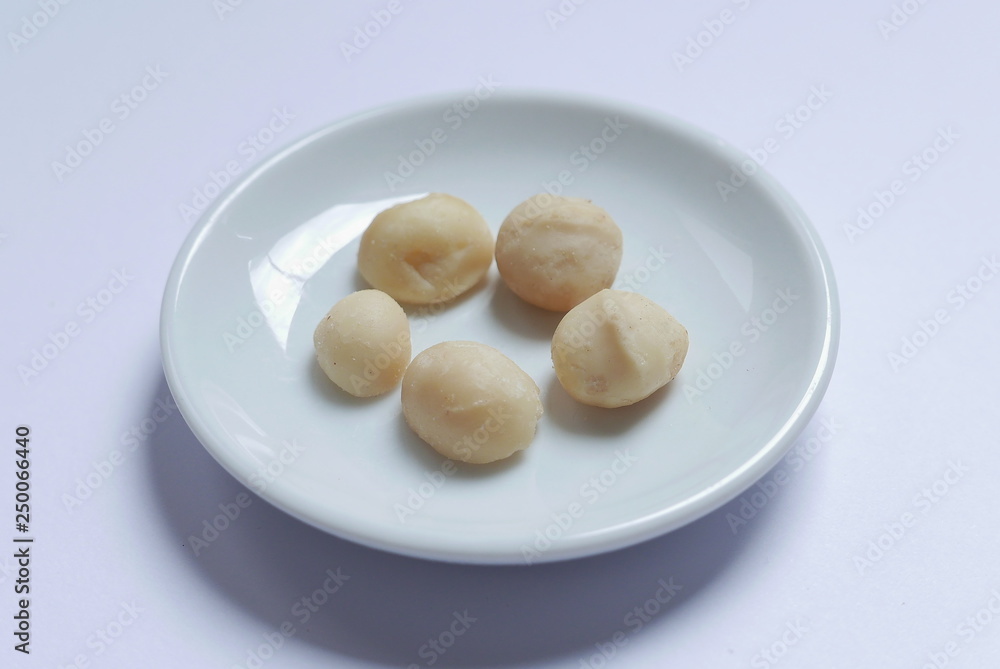 Top view of macadamia nuts in bowl on white background. Top view of macadamia nuts in bowl on white background.