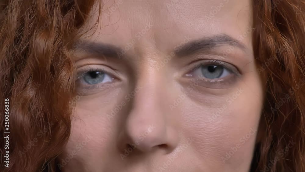 Closeup portrait of adult caucasian red-haired female face with blue eyes looking straight at camera Closeup portrait of adult caucasian red-haired female face with blue eyes looking straight at camera