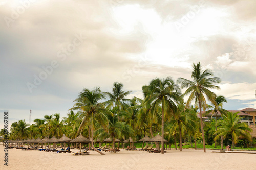  Palm trees and beach chairs on a deserted beach on Hainan Island.