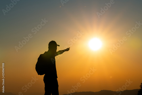 Men are climbing in the shadows in the sunset mountains, with backpacks on the top of the mountain, looking at the beautiful sky scenery, freedom concept.